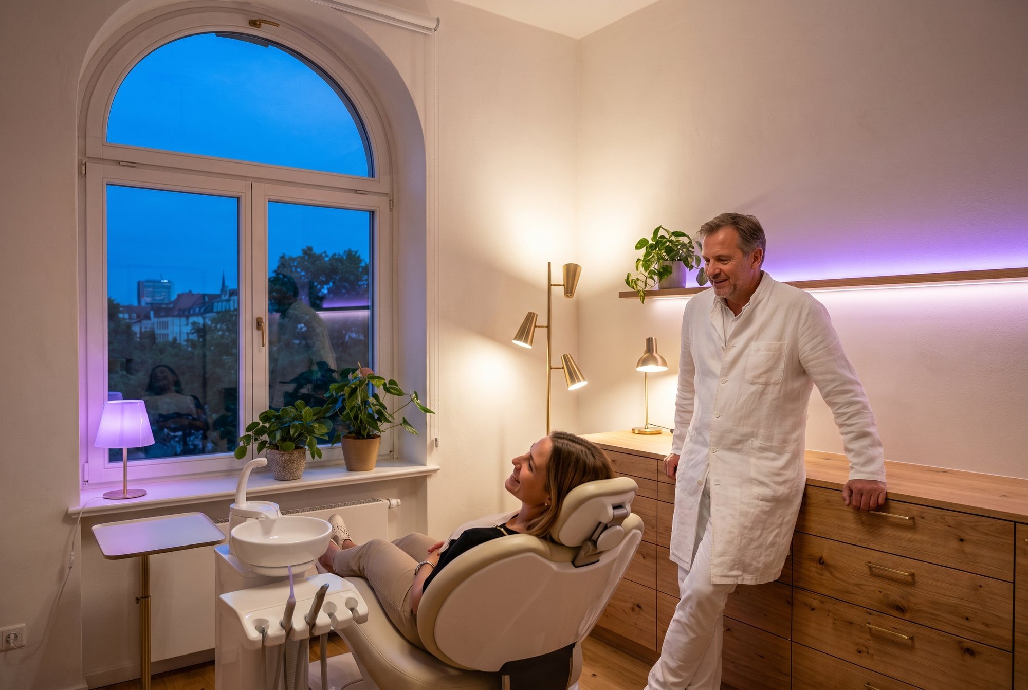 Dentist me përparëse të bardhë flet me një paciente në karrigen dentare